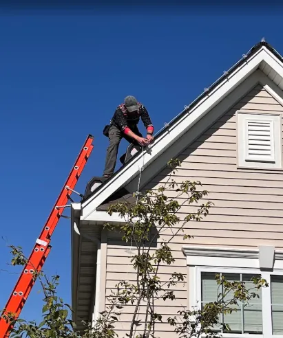 Crew member securing roofline clips at the peak from a ladder