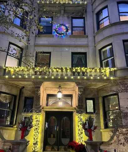 Stone commercial building with lit garland across the entrance and balcony