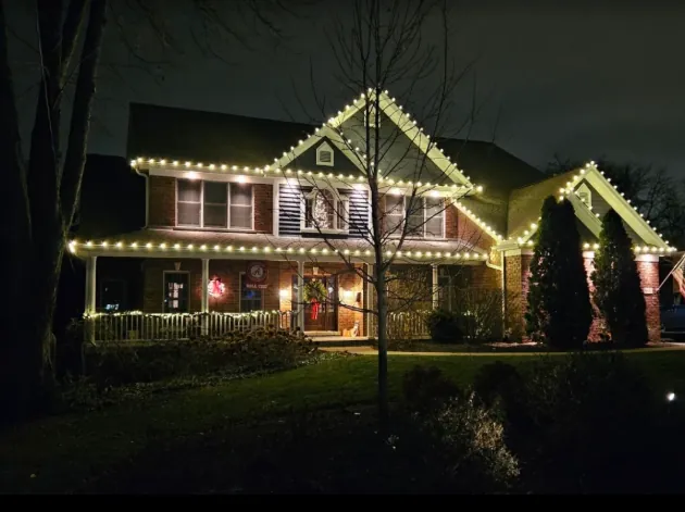 Cottage-style home with warm white roofline lights at dusk