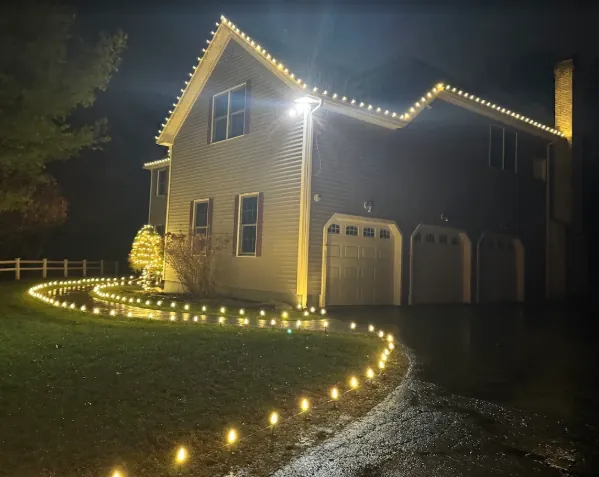 Curved driveway lined with pathway lights leading to a lit garage