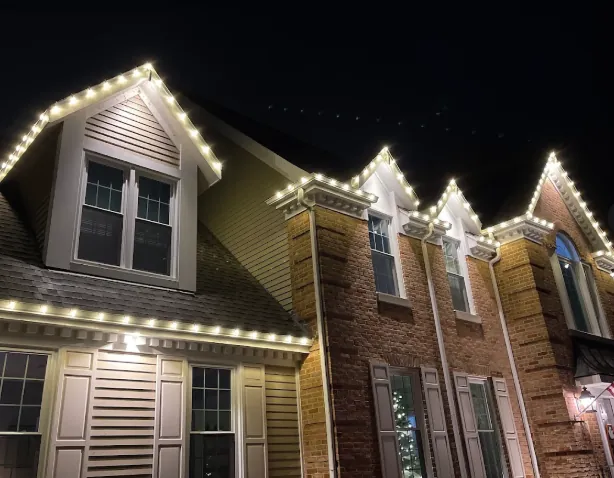 Warm white lights outlining dormers and gables on a large home