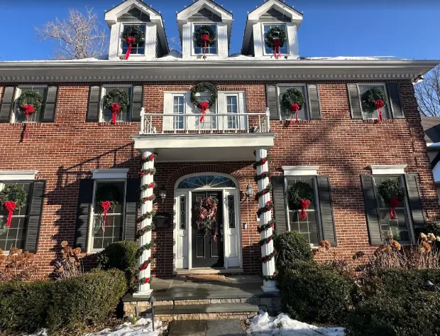 Brick colonial with red-bow wreaths in every window and candy-cane wrapped columns
