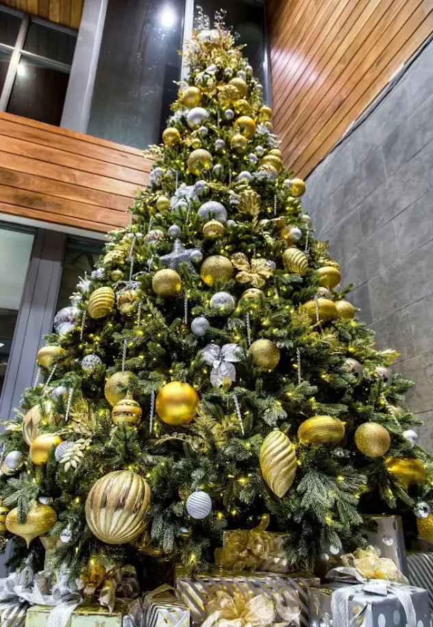 Tall commercial lobby Christmas tree decorated in gold and silver ornaments