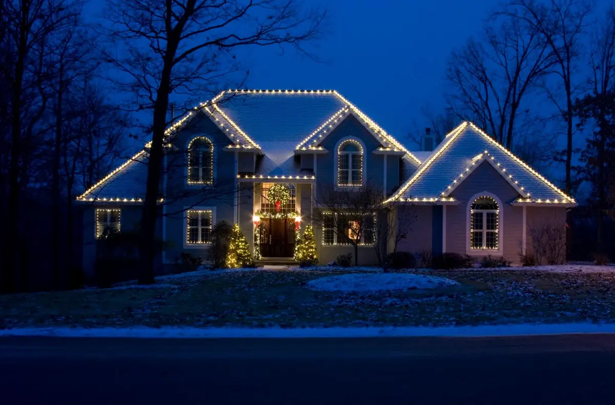 Home at twilight with every roofline, peak and window outlined in warm white lights