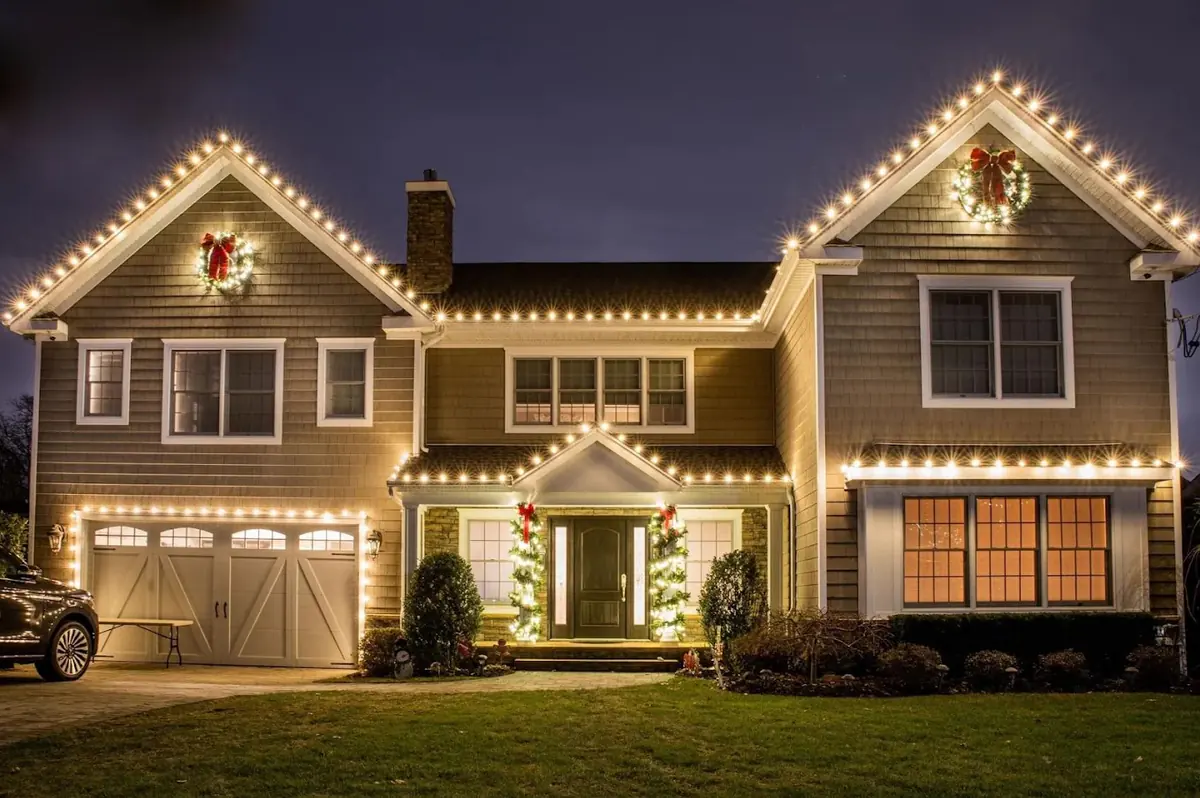 Shingle home with warm white C9 bulbs on every gable, garage and porch roofline, and lit gable wreaths